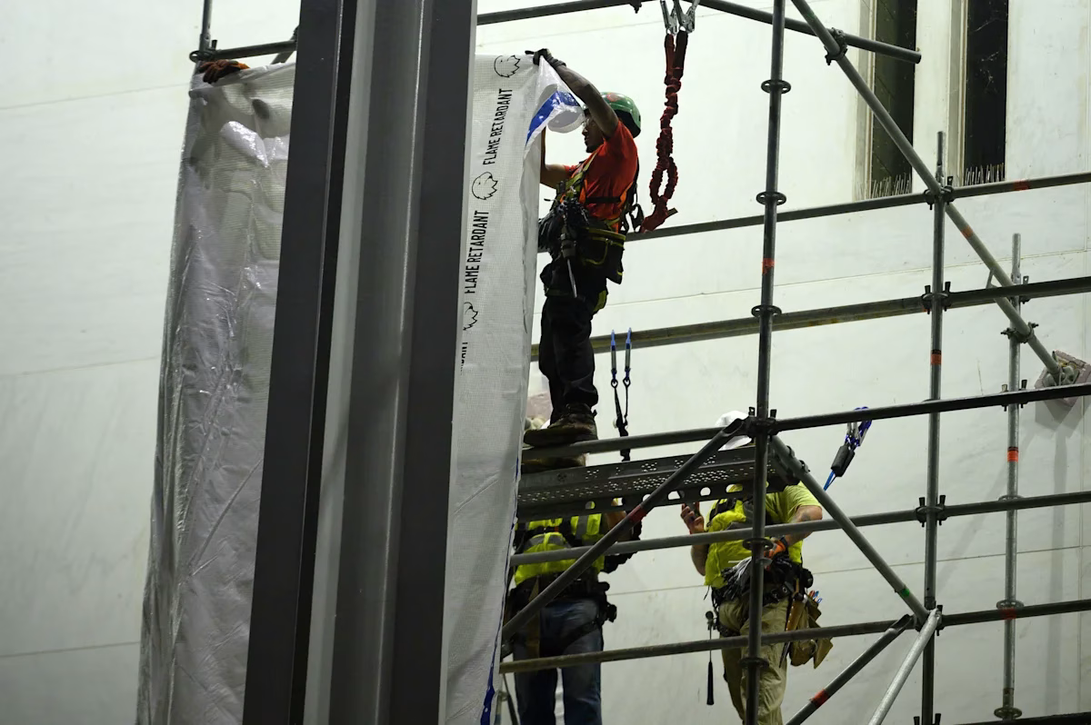 Workers hang the tarp